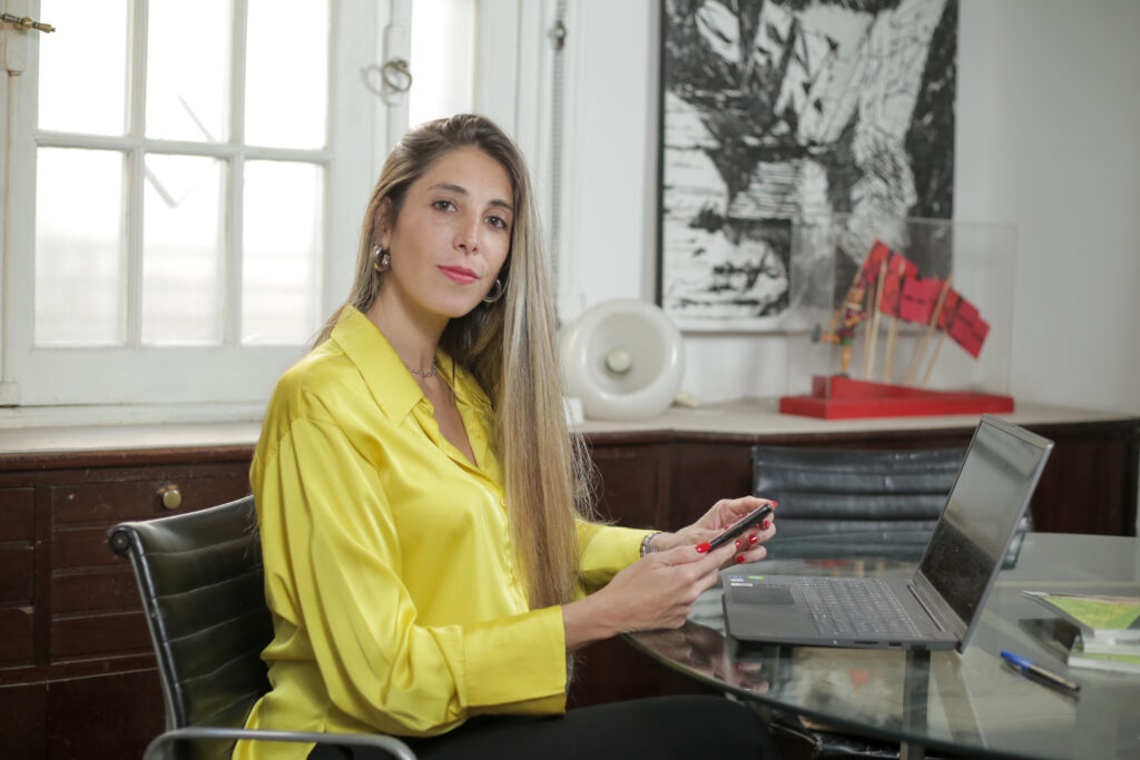 Gabriela Fernández revisando una propuesta en su teléfono junto a una notebook